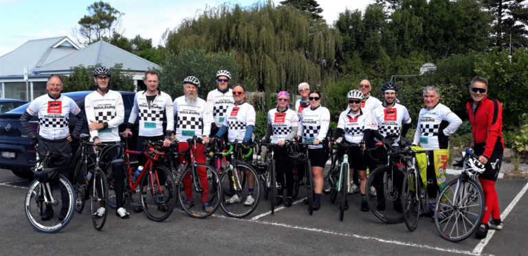 Photograph of Murray to Moyne riders wearing their chequerboard jerseys and standing with their bikes