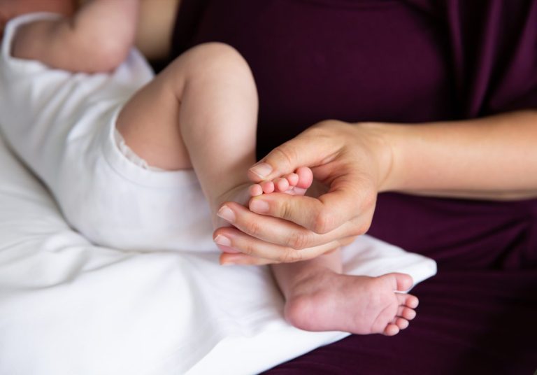 Baby on its back with mother holding his feet