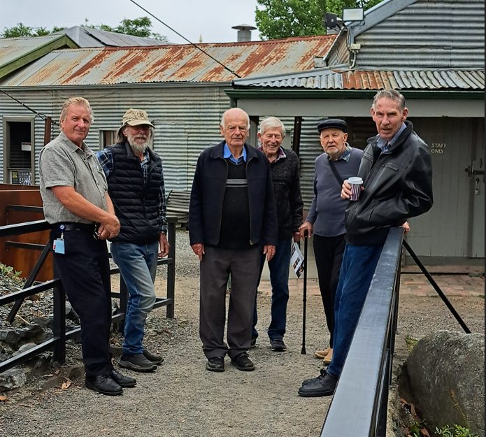 Central Deborah Gold mine visit with group of men standing in front of shed