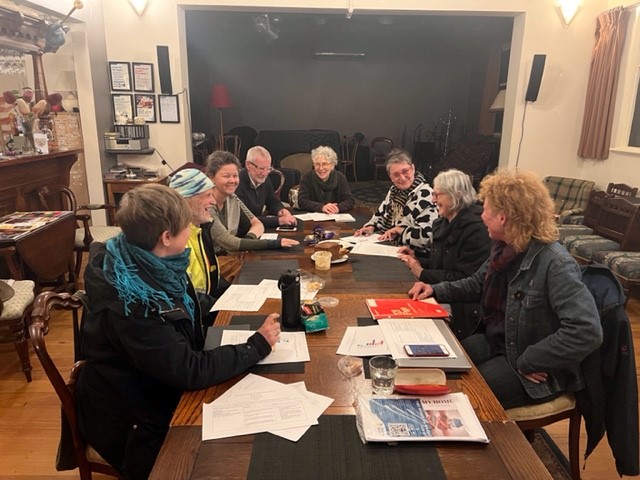 eight adults sitting at a timber table in a room