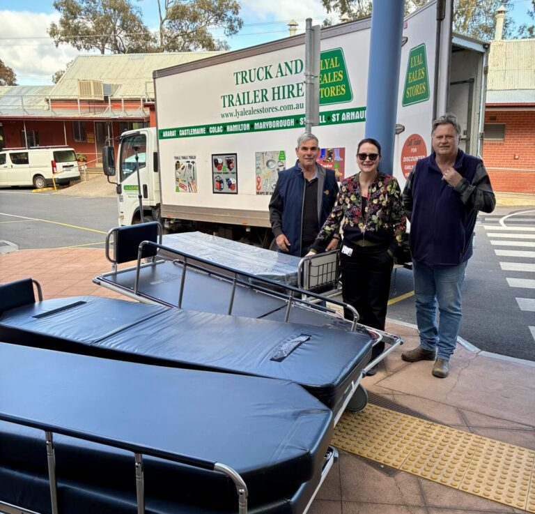 4 patient trolleys lined up in front of 3 volunteers and a delivery truck