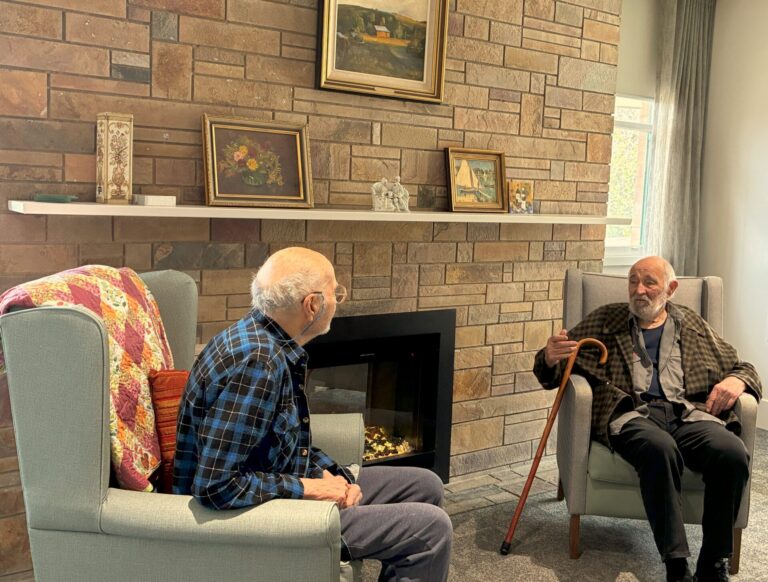 Two elderly gentlemen sitting by a fireplace