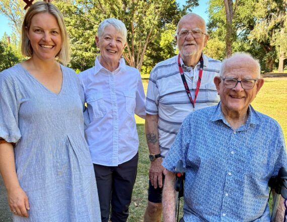 Community Health Nurse, Melodie Cameron standing with 3 participants of the walking group, one woman standing, one man standing and another man sitting on a wheely-walker.