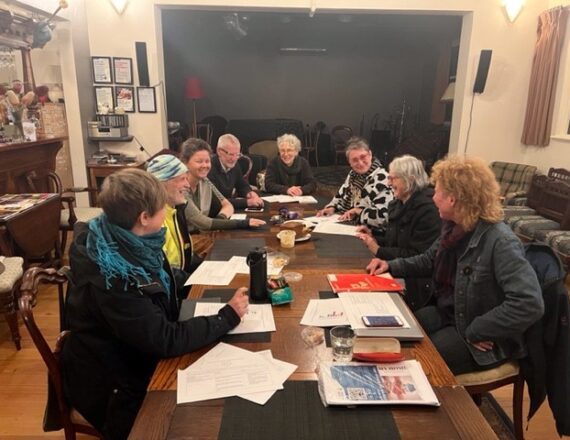 eight adults sitting at a timber table in a room